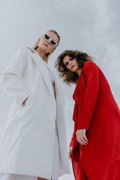 two women standing next to each other in red and white outfits, both wearing sunglasses