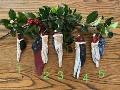 an arrangement of christmas decorations hanging from a tree branch on a wooden table with numbers in front of them