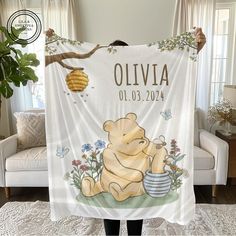 a woman holding up a personalized blanket with winnie the pooh and honeycombs