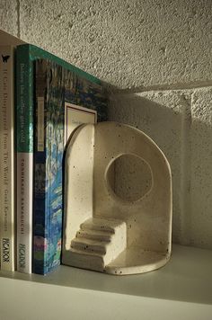 a book shelf with two books on it and a sculpture in the shape of a letter