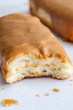 two glazed donuts sitting on top of a white surface