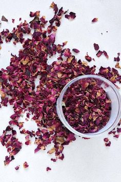 a bowl filled with dried flowers on top of a white countertop next to a glass container