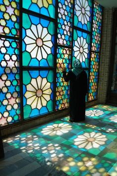 a woman standing in front of a stained glass window with sun shining through the windows