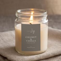 a candle that is sitting on top of a cloth next to a glass jar with the label coconut and vanilla