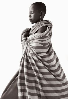 an african woman wrapped in a striped blanket, looking off to the side with her eyes closed