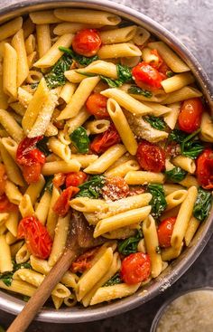 a pan filled with pasta, tomatoes and spinach