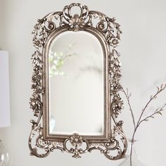 a mirror sitting on top of a table next to a vase with flowers in it