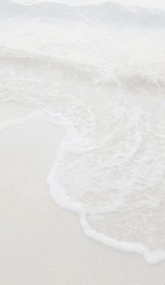 an ocean view with waves crashing on the beach and a surfboard in the foreground