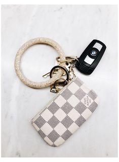 a keychain with a white and black checkerboard pattern on it, sitting next to a cell phone