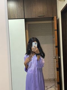 a woman in a purple dress taking a selfie with her cell phone while standing in front of a mirror