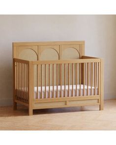 a wooden crib in a room with white walls and wood flooring on the ground