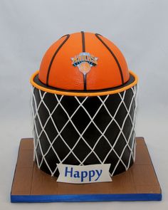 an orange basketball sitting in a basket on top of a wooden stand that says happy