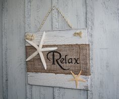 a sign that says relax with starfish on the front and side of it hanging from a rope