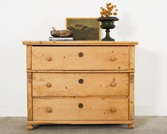 a wooden dresser with two drawers and a painting on top