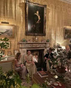 two women sitting in front of a fire place next to a painting on the wall