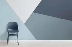 a chair sitting in front of a wall painted with blue and grey geometric shapes on it