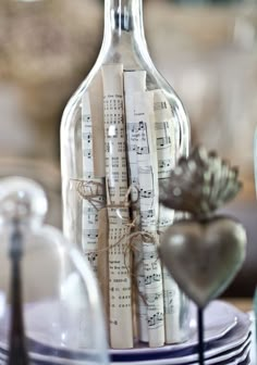 an empty bottle with sheet music notes in it sitting on a table next to plates and silverware