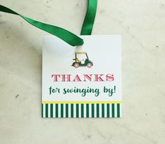 a green ribbon hanging from a white tag that says thanks for swinging by