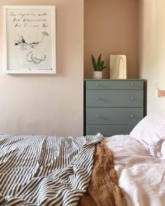 an unmade bed in a bedroom with pink walls and striped comforter on it