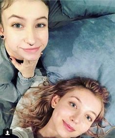 two women laying on top of a bed next to each other with their hands under their chins