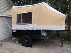 an rv parked in front of a house with a tent attached to the back of it