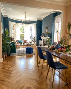 a living room filled with lots of furniture and plants on top of wooden flooring