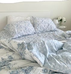 an unmade bed with blue and white comforter on it's headboard