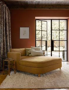 a living room with red walls and wooden flooring, large window to the outside