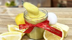 a jar filled with lemon curd next to sliced lemons