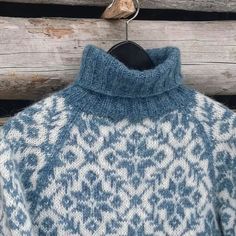 a blue and white sweater is hanging on a wooden wall with a bird perched on it