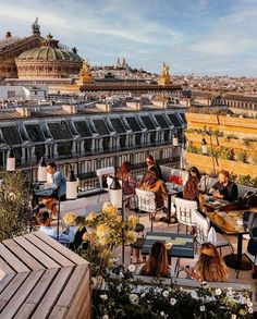 people sitting at tables on the roof of a building in paris, overlooking the city