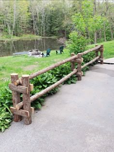 a wooden fence made out of logs in front of a pond and picnic area with benches