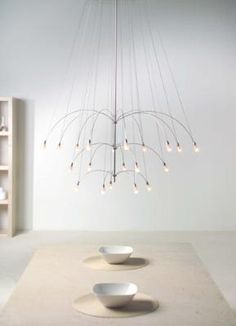 two white bowls sit on the floor in front of a chandelier with lights hanging from it