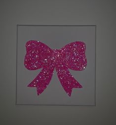 a pink bow on a white background in a square frame with silver glitter paper underneath