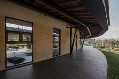 an empty walkway next to a building with large windows on the side and grass in front of it