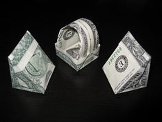 three origami balls and one dollar bill on a black table with dark background