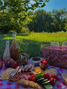 a picnic is set out on the grass with fruit, cheese and wine in bottles