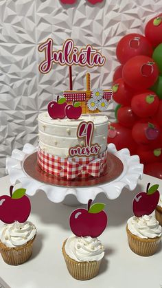 an apple themed birthday cake and cupcakes on a table