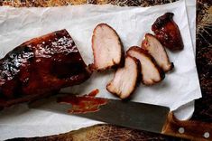 sliced pork on parchment paper with knife next to it