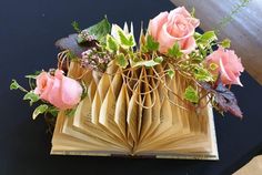 an open book with flowers on it sitting on a table