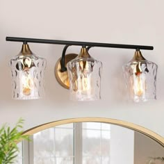 three light bathroom fixture with clear glass shades and gold accents in a white walled room