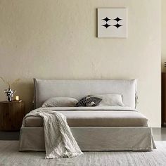 a bedroom with a bed, nightstands and pictures on the wall above it in neutral colors