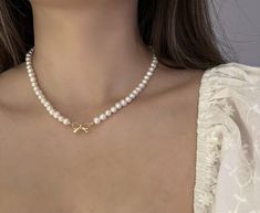 "This charming bow freshwater pearl necklace is both cute and beautiful, the bow was crafted with high-quality 14k gold plating over sterling silver. It's 100% hypoallergenic and friendly to sensitive skin. Perfect for a casual and cute T-shirt look or effortlessly complements dresses. 🤍 MATERIAL 🤍 Freshwater pearls --- real pearls, formed in mussels living in freshwater, known for their beauty and affordability Bow: 14K Gold Plated over 925 sterling silver  Extender: 14K Gold Plated 🤍 SIZE 🤍 5-6mm freshwater pearls 16'' (2\" extender included) 17'' (2\" extender included) 18'' (2\" extender included) 20'' (2\" extender included) (Dm for custom length) 🤍 WARRANTY 🤍 We are confident about the quality of our jewelry, but sometimes things break. If anything happens within 90 days (with Pearl Bow Necklace, Bow Choker, Crochet Necklace Pattern, Pearl Necklace Choker, Pearl Bow, Basic Jewelry, Ribbon Necklace, Bow Necklace, Bow Jewelry