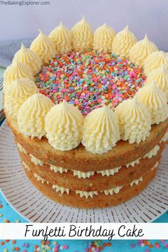 a cake with white frosting and sprinkles on top is sitting on a plate