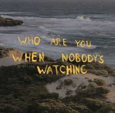 the words who are you when nobody's watching written in yellow on top of sand dunes