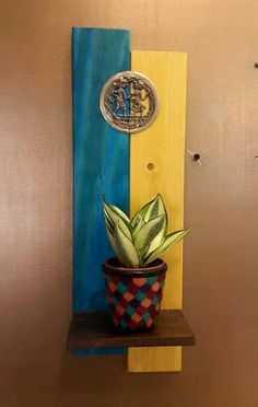 a potted plant sitting on top of a wooden shelf next to a metal medallion