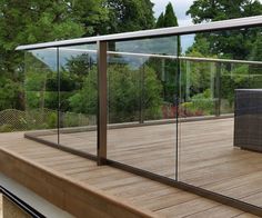 an outdoor deck with glass railing and wicker chair