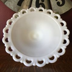 a white plate sitting on top of a wooden table next to a clock with roman numerals