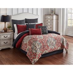 a bed in a bedroom with red and black pillows