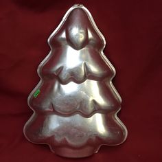 a metal christmas tree shaped cake pan on a red background